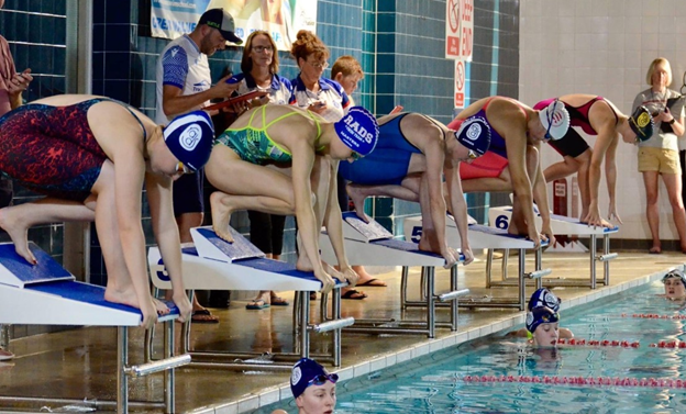 Focused young swimmers at the starting line, ready to launch into a competitive swim race